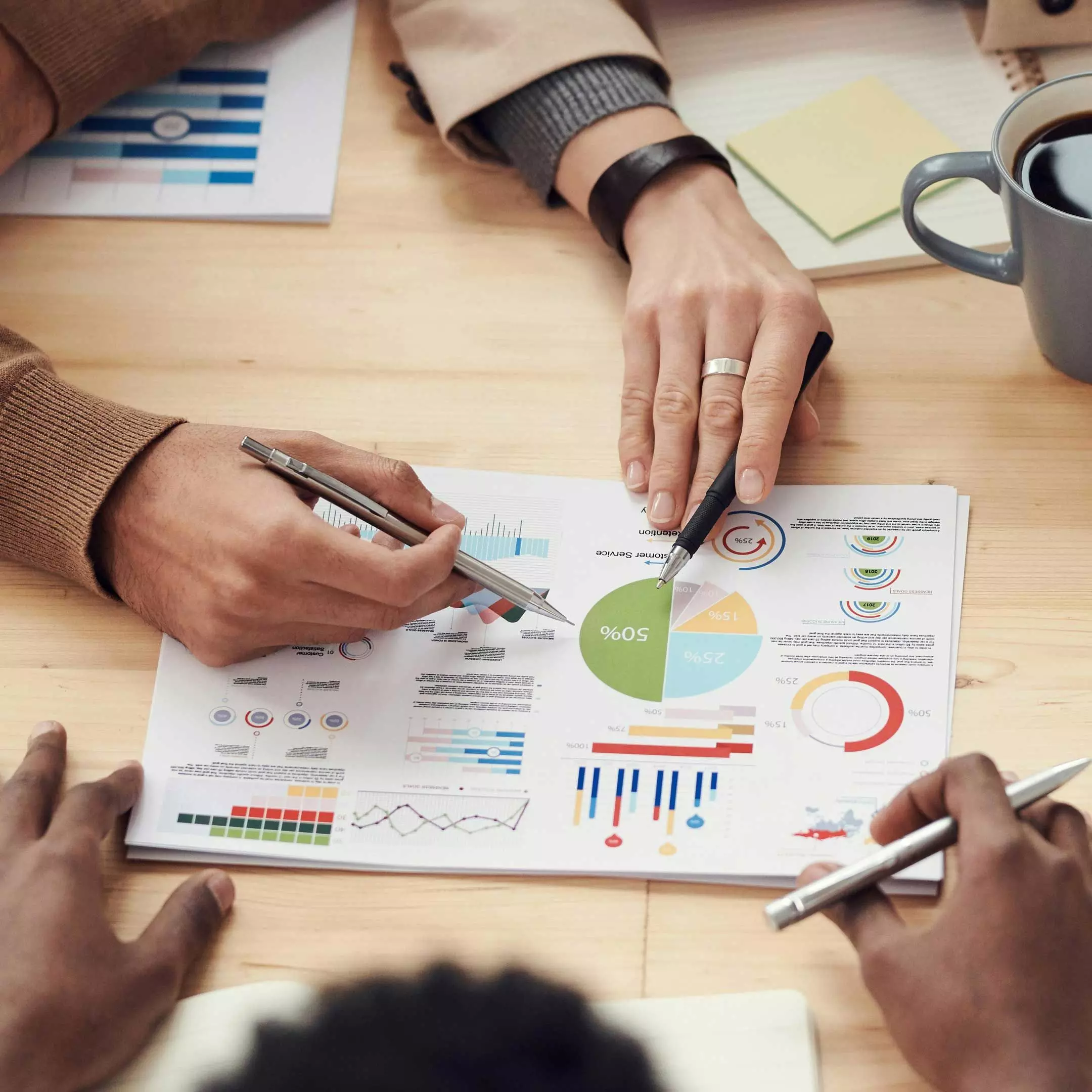 Image of three people reviewing financial data printed on a piece of paper